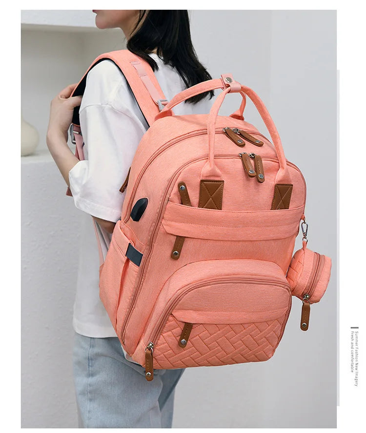 Sac a langer rose muni de nombreux compartiments, de poches laterales et d'une pochette a tetine amovible pour tout organiser facilement.