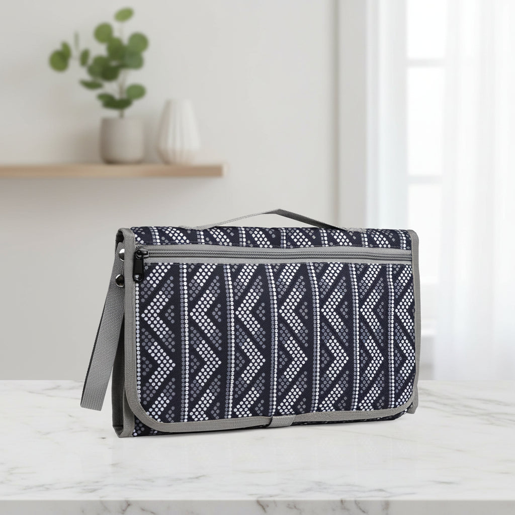 Station de change nomade repliee en format pochette, motif graphique noir et gris, pratique a emporter en voyage ou en balade avec bebe.