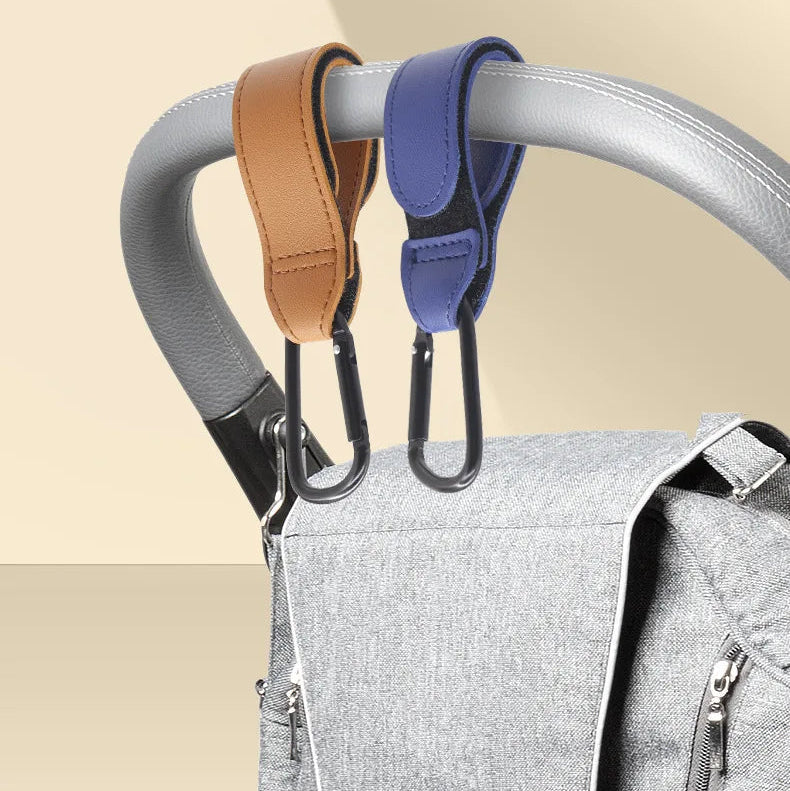 Attache poussette universelle en simili cuir avec mousqueton pour suspendre facilement un sac a langer sur la barre.