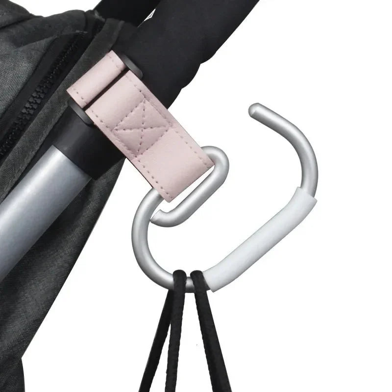 Crochet rose fixe sur la barre d'une valise, montrant sa polyvalence pour suspendre des sacs en voyage.