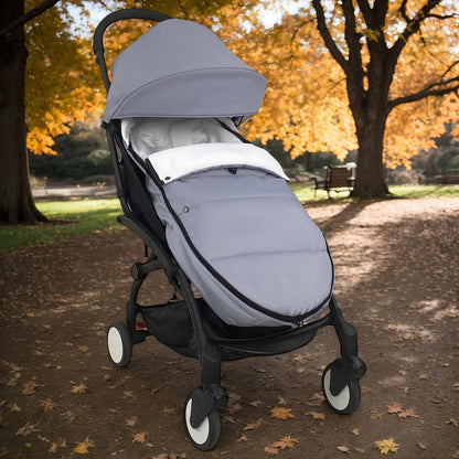 Chancelier gris sur une poussette dans un parc ensoleille, offrant confort et chaleur pour les promenades en famille.