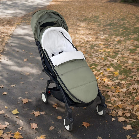 Chancelier vert kaki installe sur une poussette lors d'une balade d'automne, gardant bebe au chaud parmi les feuilles mortes.