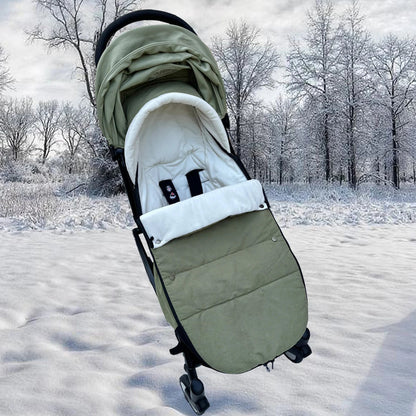 Chancelière kaki installée sur une poussette dans un paysage enneigé démontrant sa protection thermique contre le grand froid.