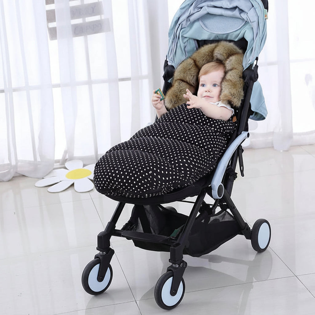 Bebe installe confortablement dans sa poussette avec la chanceliere a pois qui le protege du froid lors des balades hivernales.