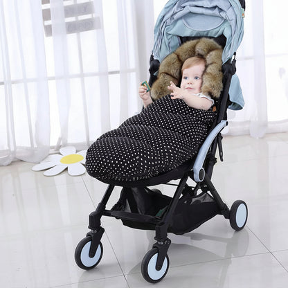 Bebe installe confortablement dans sa poussette avec la chanceliere a pois qui le protege du froid lors des balades hivernales.