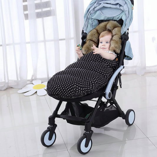 Bebe installe confortablement dans sa poussette avec la chanceliere a pois qui le protege du froid lors des balades hivernales.