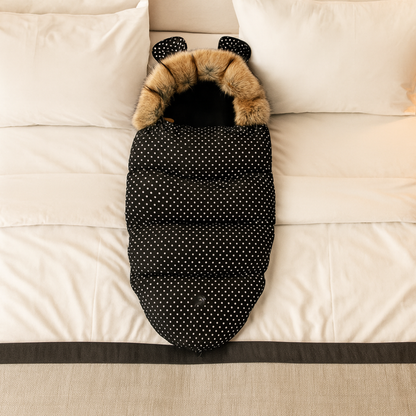 La chanceliere a pois deployee sur un lit montre sa capuche ourson et sa forme cocon adaptee aussi au sommeil a la maison.