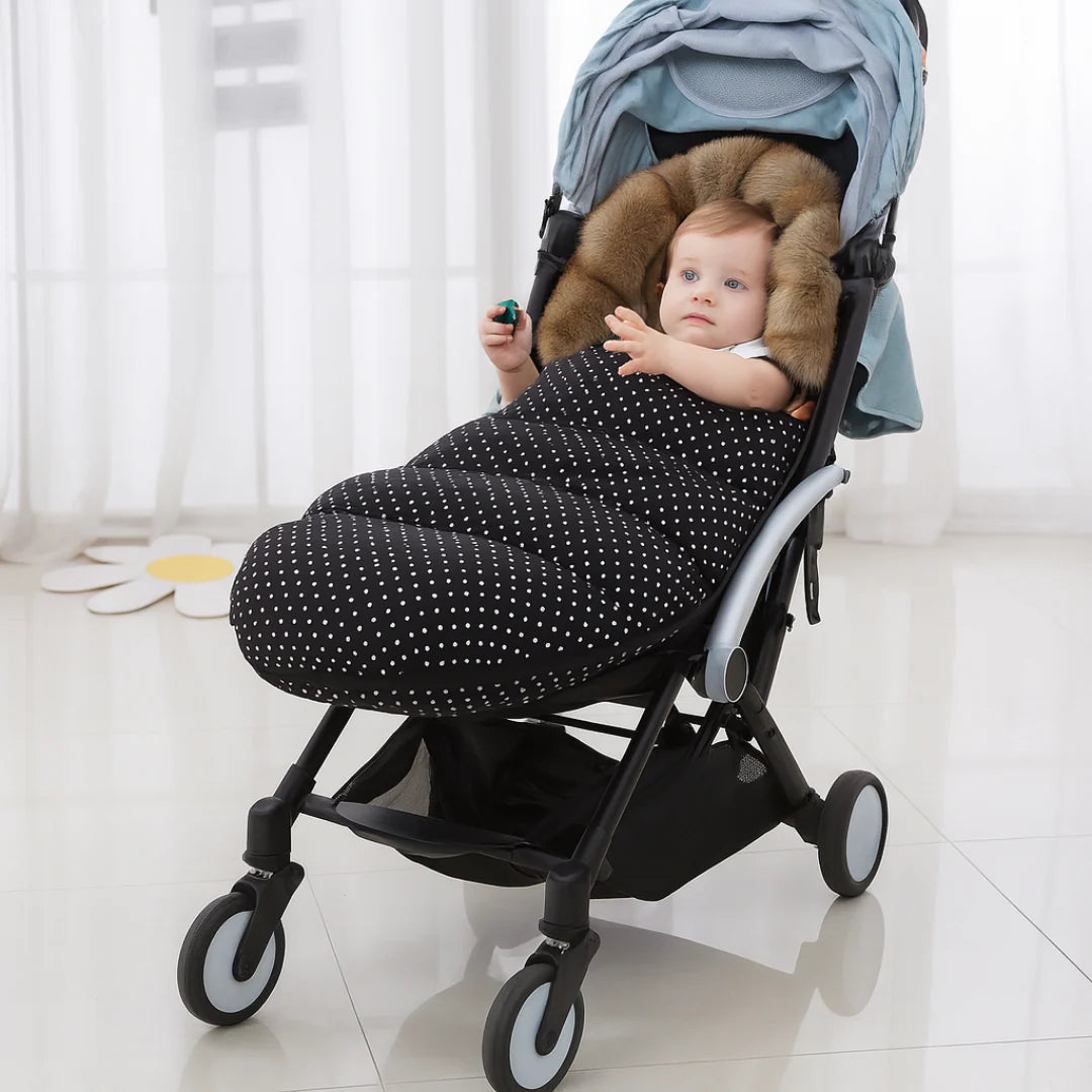Enfant bien au chaud dans la chanceliere a pois installee sur une poussette compacte, prete pour une promenade en hiver.