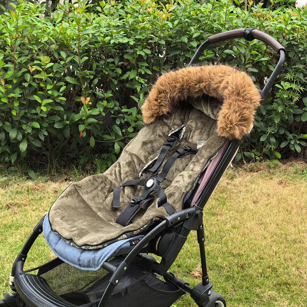 Chanceliere kaki ouverte et fixee sur une poussette dans un jardin, prete a accueillir bebe pour une balade hivernale.