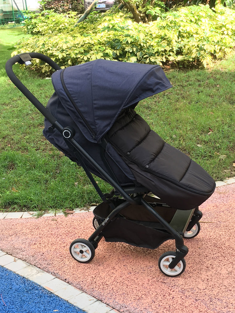 Chanceliere noire montee sur une poussette compacte en exterieur, offrant une protection sobre et elegante.