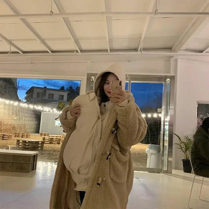 Maman portant son nourrisson bien couvert grace au manteau de portage en sherpa lors d une sortie en soiree hivernale.