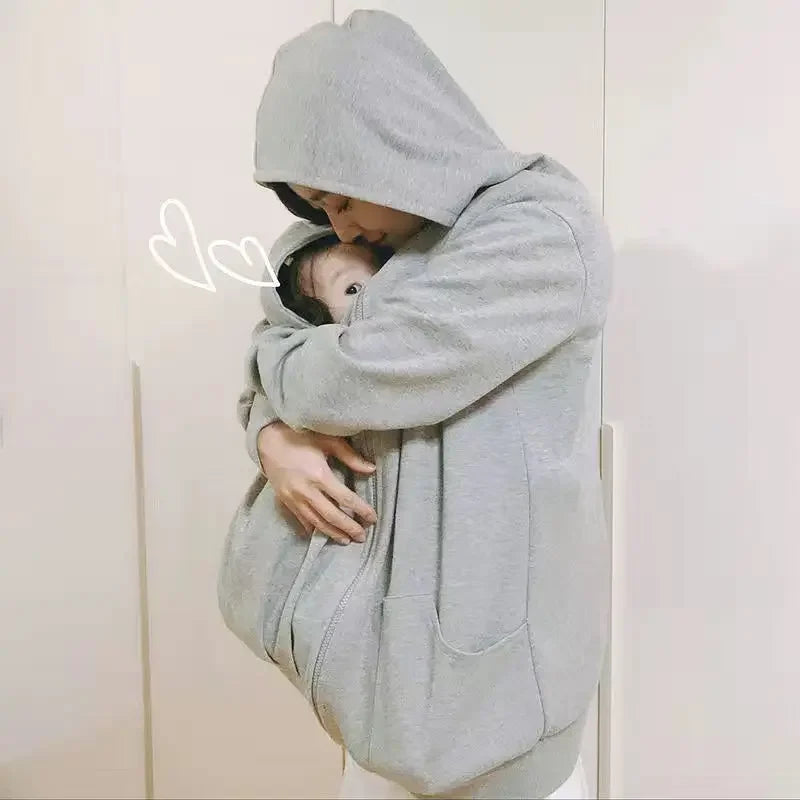 Bebe protege et blotti dans le manteau de portage pendant que sa maman l embrasse tendrement.