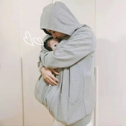 Bebe protege et blotti dans le manteau de portage pendant que sa maman l embrasse tendrement.