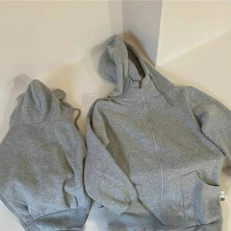 Manteau de portage gris avec double capuche pour maman et bebe, presente a plat pour montrer la coupe evolutive.