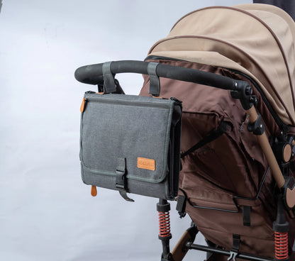 Matelas nomade gris accroche au guidon de la poussette pour garder le necessaire de change a portee de main en promenade