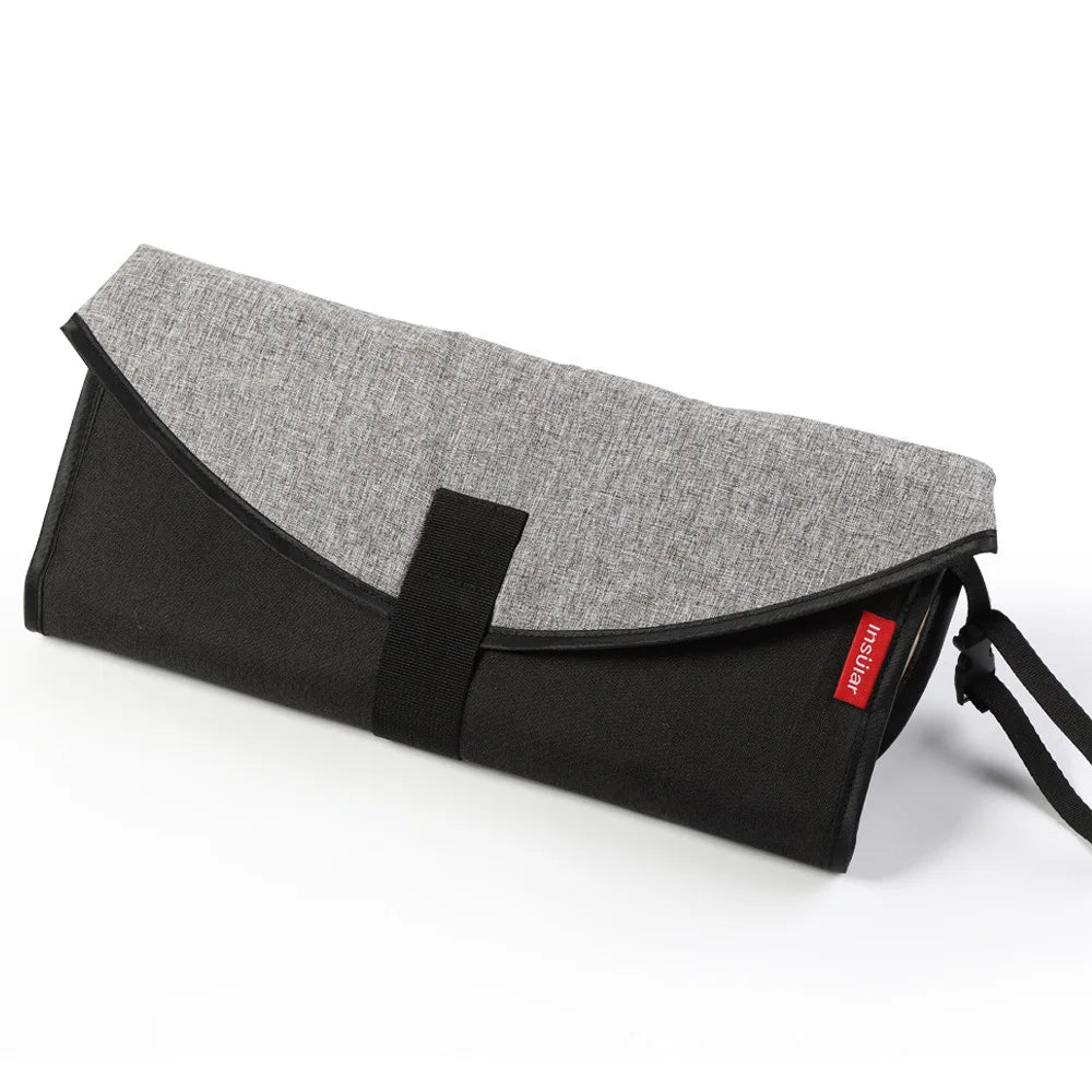 Version noire et grise du matelas a langer portable, avec dragonne pour l'accrocher facilement en deplacement.