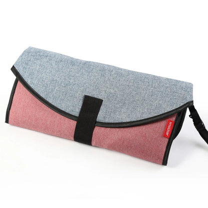 Matelas a langer nomade replie dans son coloris rose et gris, format pochette qui tient dans une seule main.