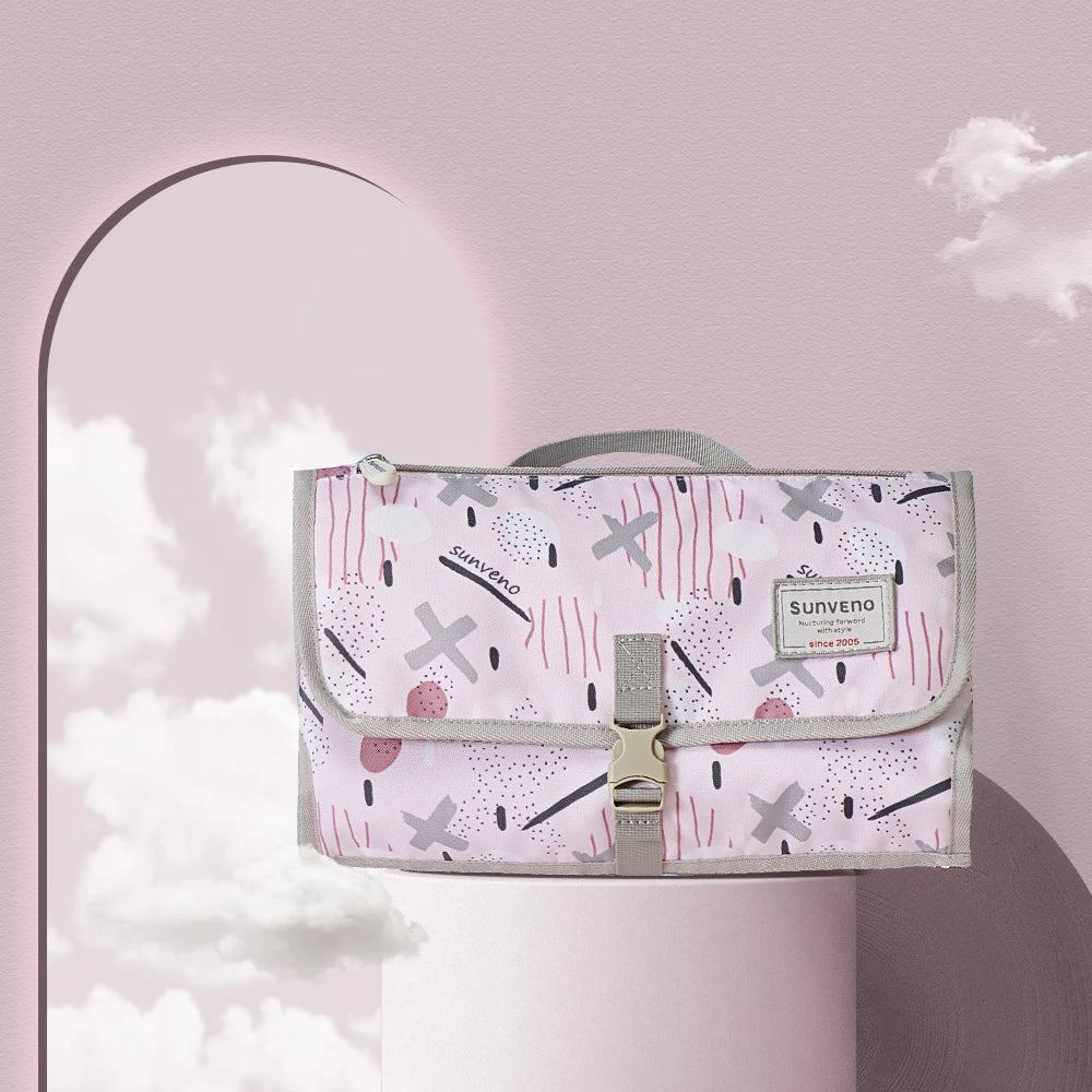 Matelas a langer nomade Sunveno en coloris rose a motifs graphiques, compact et elegant pour les sorties quotidiennes.