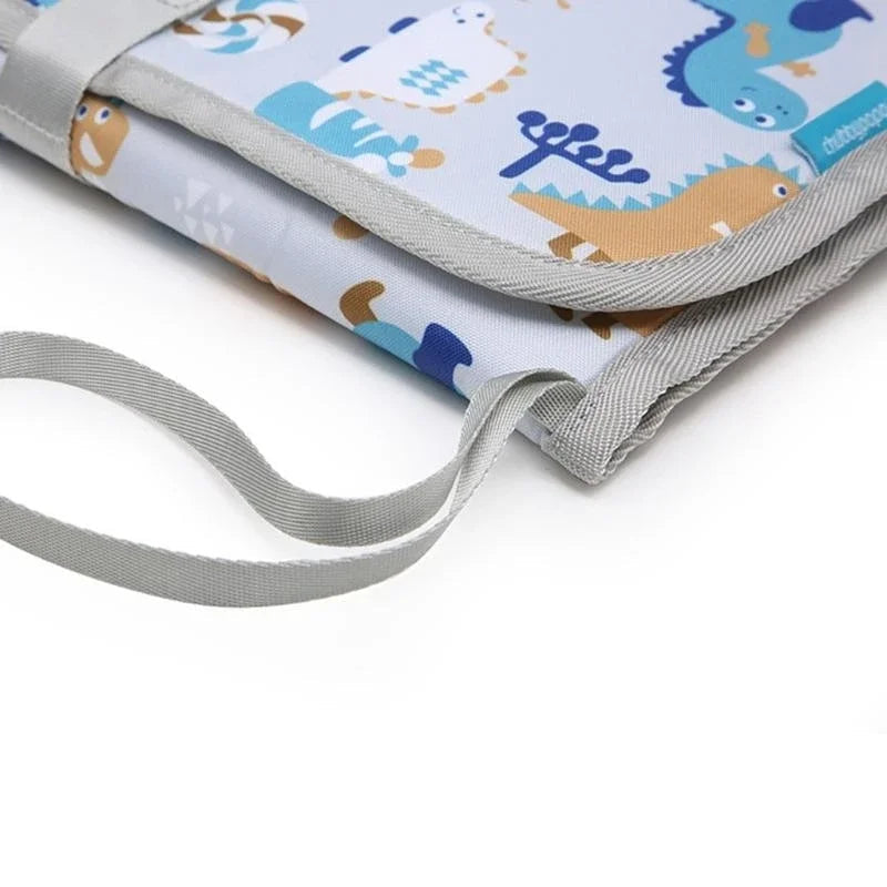 Gros plan sur la dragonne grise et les coutures renforcees du matelas a langer nomade, permettant de le suspendre facilement a une poussette ou un sac.