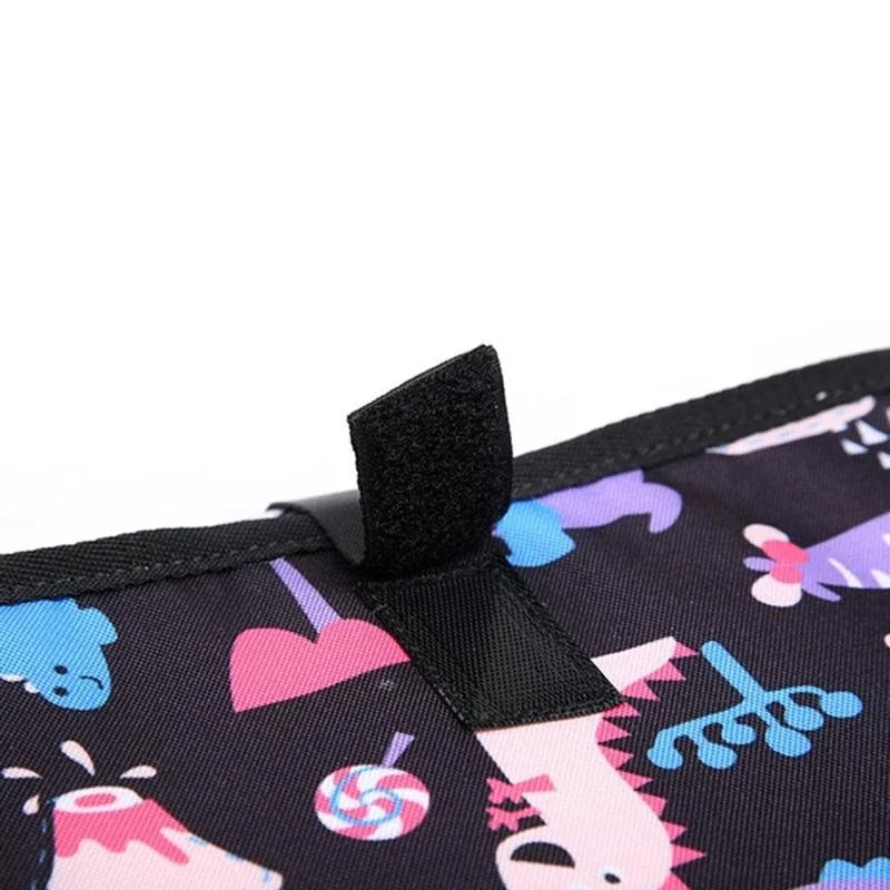 Detail de la patte de fermeture velcro noire qui maintient le matelas a langer plie fermement pendant les deplacements.