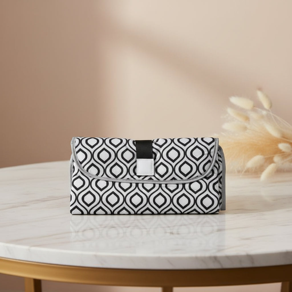Matelas a langer nomade plie au format pochette motif geometrique noir et blanc, facile a glisser dans un sac a langer.