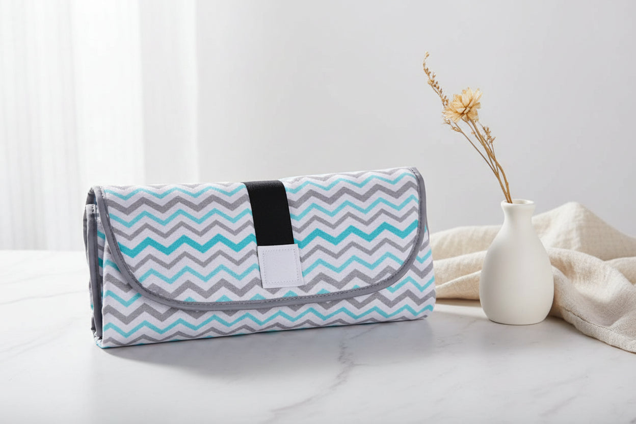 Matelas a langer nomade referme en pochette motif chevron bleu, compact et pratique a emporter partout.