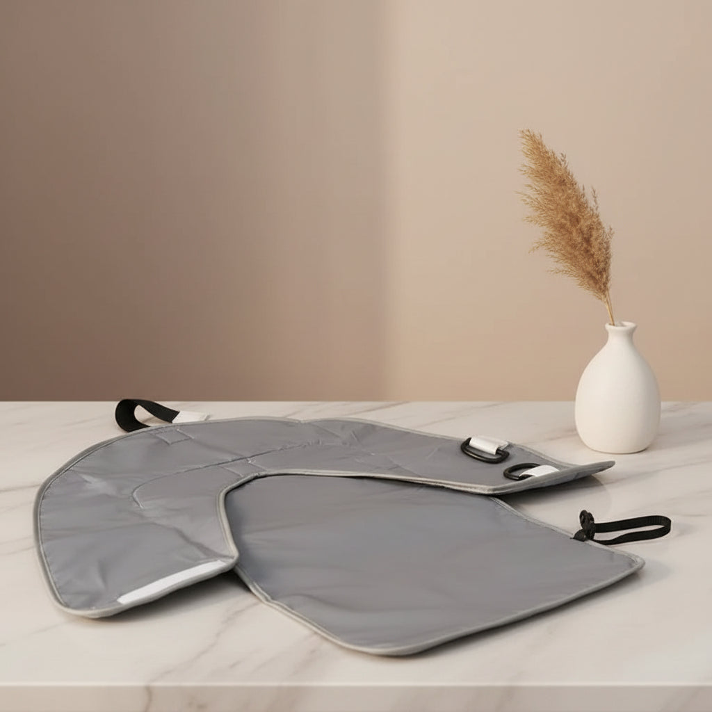 L'envers gris impermeable du matelas a langer s'essuie facilement et se ferme grace a sa sangle pour un rangement compact.