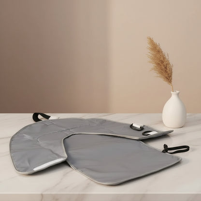 L'envers gris impermeable du matelas a langer s'essuie facilement et se ferme grace a sa sangle pour un rangement compact.