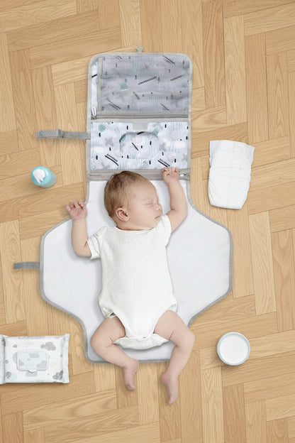 Bebe allonge confortablement sur le matelas a langer deploye avec ses poches organisatrices integrees pour un change complet partout.