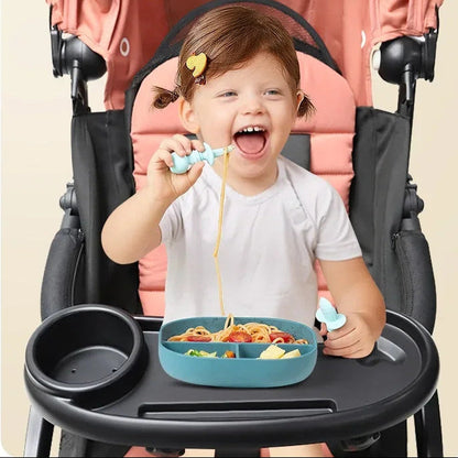 Petite fille mangeant seule ses pates depuis le plateau fixe a la poussette, favorisant l'autonomie au repas.