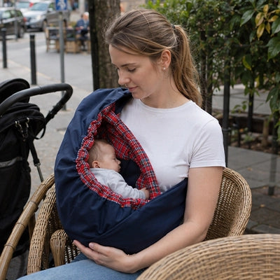 Assise en terrasse, une maman profite du porte-bebe hamac pour cocooner bebe tout en restant installee confortablement.