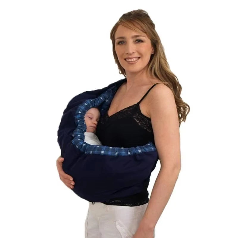 Maman porte son nouveau-ne endormi dans le porte-bebe hamac, une position couchee ideale pour les premiers mois.