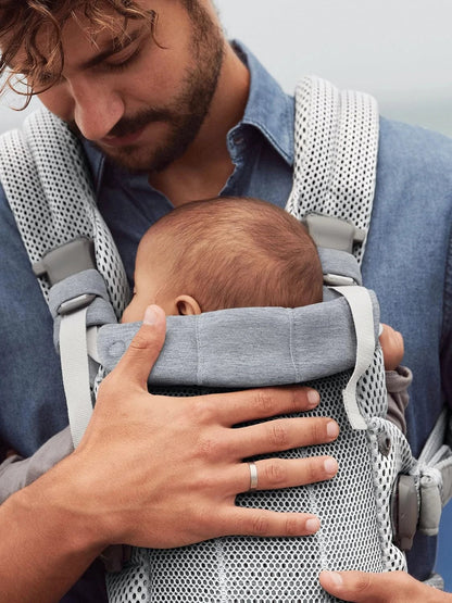 Gros plan sur l'appui-tete rembourre du porte bebe qui soutient la nuque du nouveau-ne endormi contre son papa.