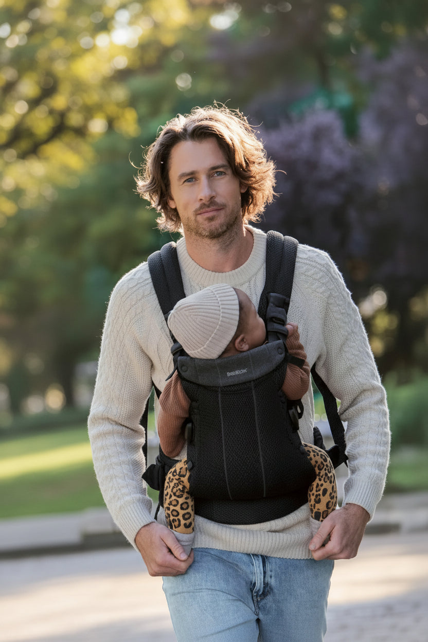 Porte bebe physio noir porte par un papa en balade, offrant un maintien ergonomique du nouveau-ne.