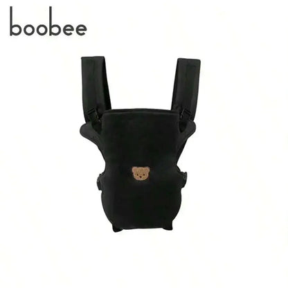 Porte-bebe physiologique noir avec motif ourson brode, vue de face montrant les bretelles rembourrees et l'assise ergonomique.