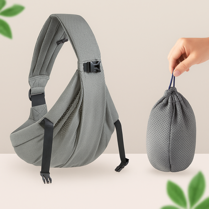 Porte-bebe sling gris presente seul avec son sac de rangement compact tenu a la main, ideal pour le glisser dans un sac a langer.