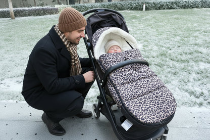 Chanceliere installee sur une poussette lors d'une balade dans la neige, protegeant efficacement bebe du froid hivernal.