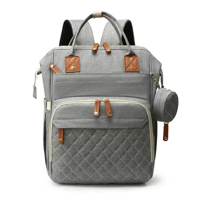 Sac a dos a langer avec lit en gris clair, poche frontale matelassee et pochette a tetine pour rester organise en deplacement.