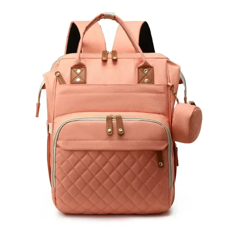 Sac a dos a langer avec lit en teinte rose corail, poche matelassee et finitions cuir pour un style elegant au quotidien.