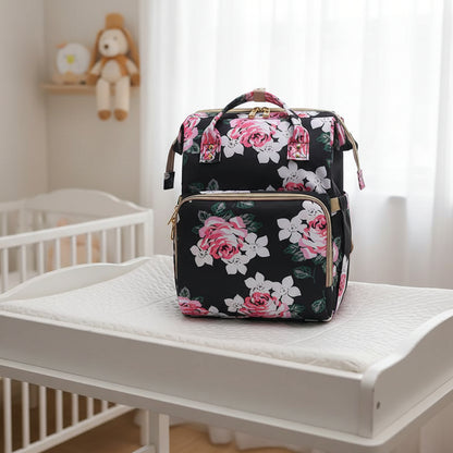 Sac a dos a langer noir a roses roses, coloris chic ideal pour les parents recherchant un accessoire discret et elegant.