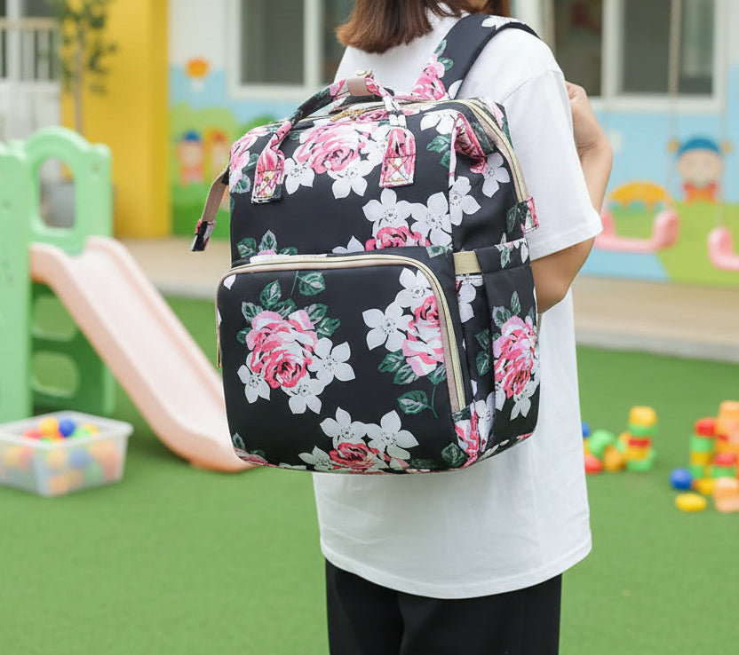 Sac a langer noir fleuri porte sur le dos, laissant les mains libres pour s'occuper de bebe pendant les sorties.
