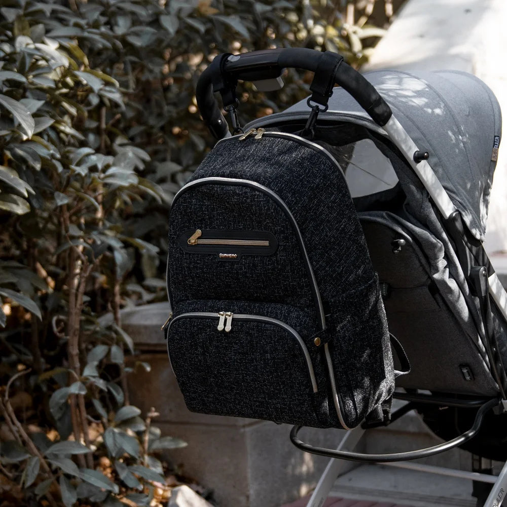 Sac a langer a dos accroche a une poussette lors d'une balade, liberant les mains des parents en promenade avec bebe.