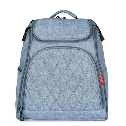 Sac a langer a dos en coloris bleu denim avec poches laterales, presente de face pour montrer sa finition elegante.