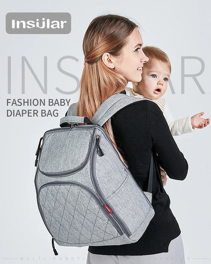 Maman elegante portant le sac a langer a dos gris, un modele mode pense pour accompagner les parents actifs.