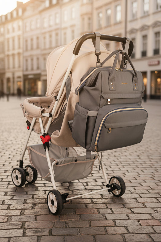 Sac a langer gris suspendu au guidon d'une poussette grace a ses sangles amovibles, ideal pour les sorties avec bebe.