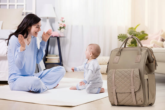 Maman jouant avec son bebe a la maison, le sac a langer multifonction pose a cote comme accessoire indispensable du quotidien des parents.