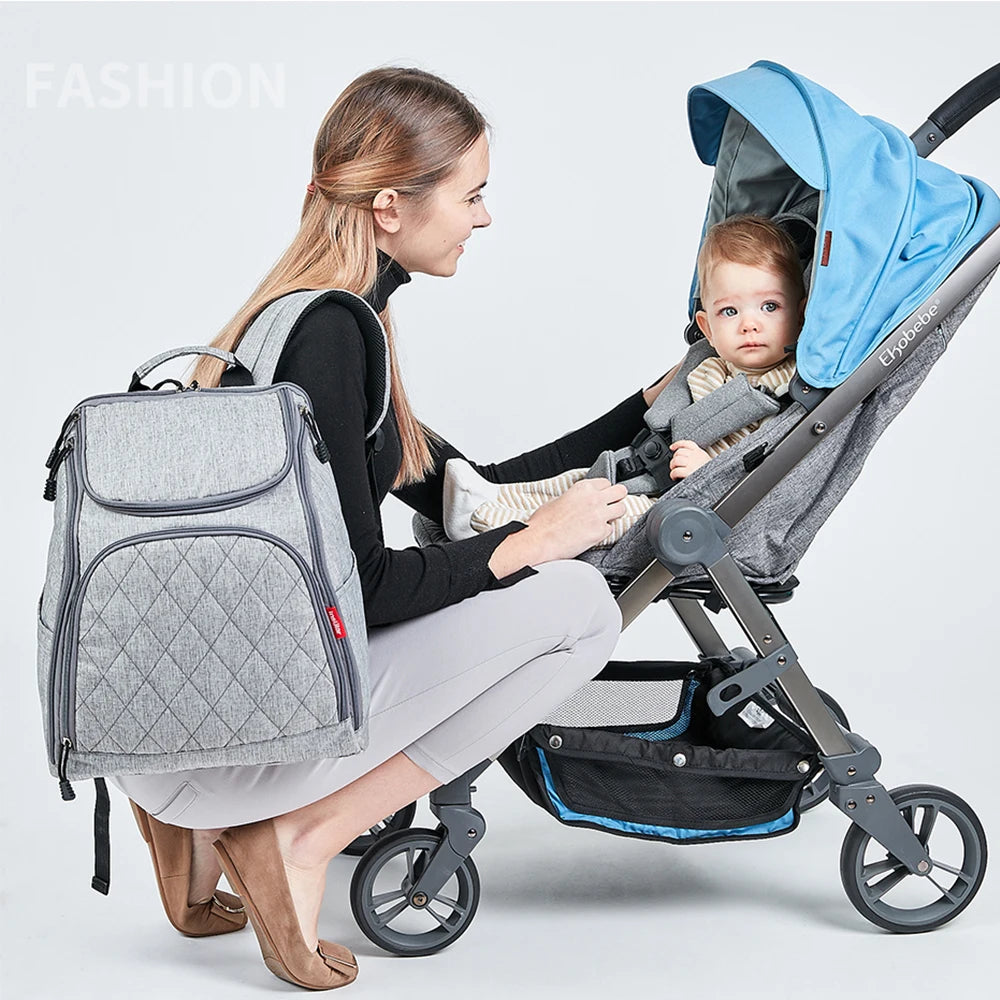 Maman ajustant son bebe en poussette avec le sac a langer sur le dos, ideal pour les promenades en ville.