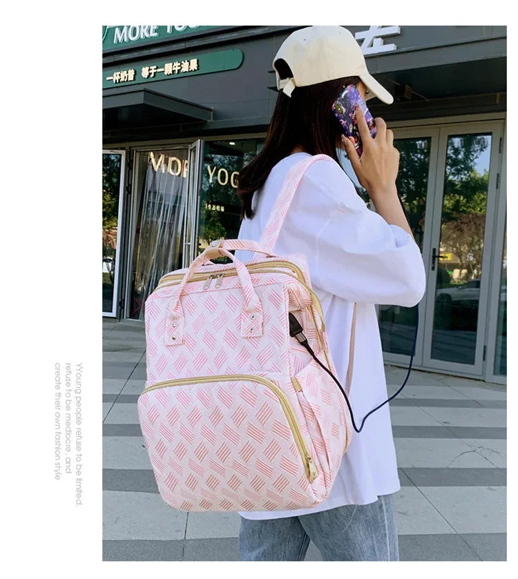Maman rechargeant son telephone via le port USB du sac tout en marchant, illustrant sa fonction nomade.