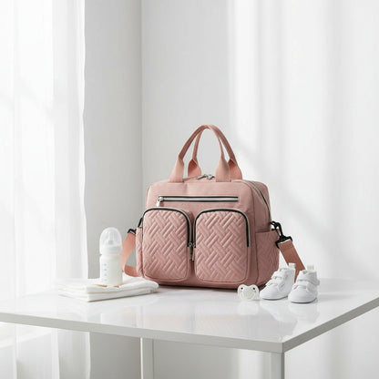 Sac a langer bandouliere rose poudre au design matelasse tendance, parfait pour les sorties avec bebe tout en restant chic.