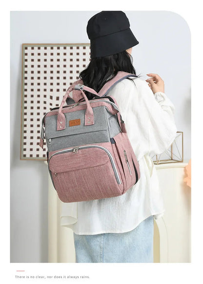 Femme portant le sac a langer sur le dos, laissant les mains libres pour s'occuper de bebe.